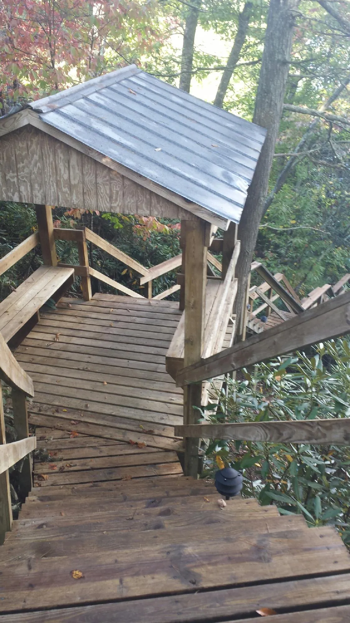 Metal roofed shelter over wooden steps on a wooded walkway — Skylight Repair & Installation work by our crew in Bethpage